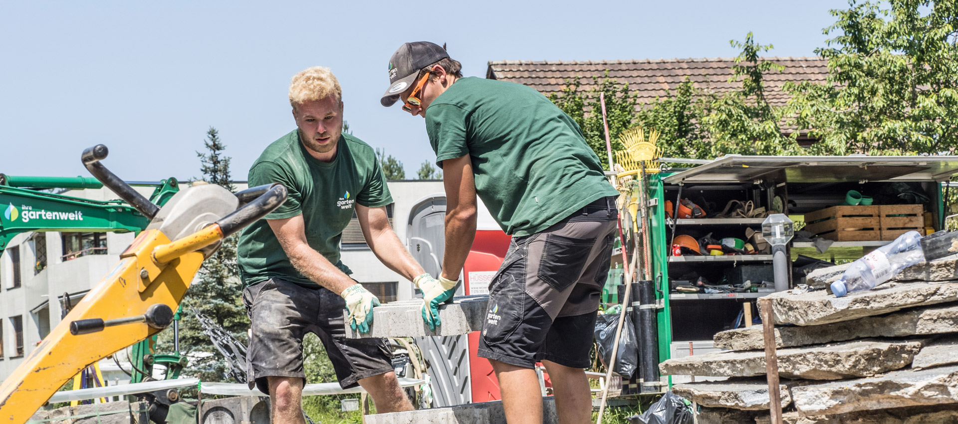 Zwei Gärtner heben Betonplatte im Gartenbau.