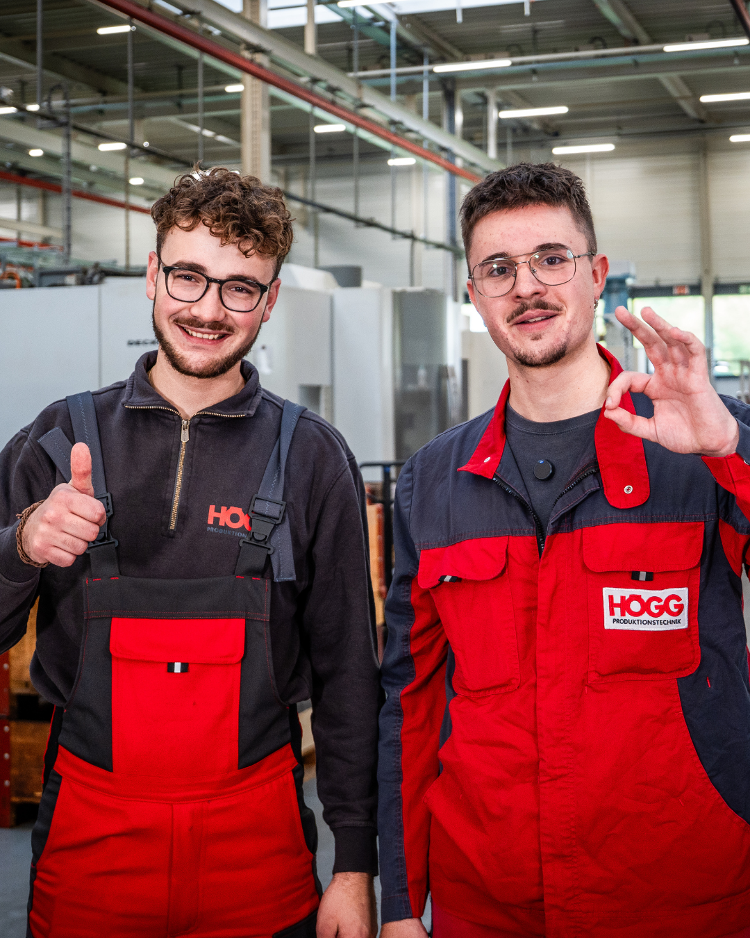 Zwei Mechaniker in Werkhalle zeigen Daumen hoch